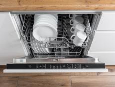 Dishwasher with clean dishes in a white kitchen