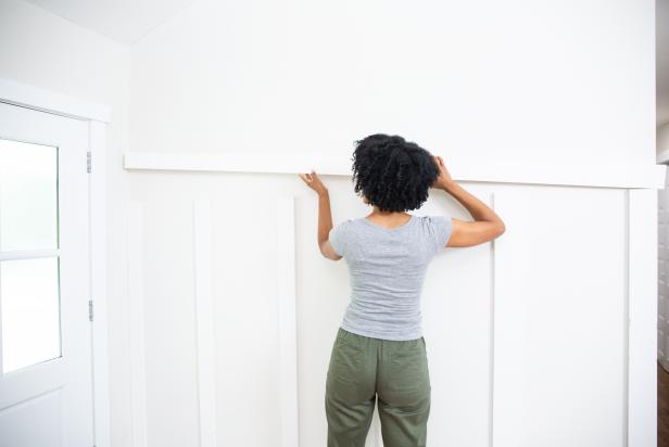 The next step in this DIY accent wall project is to position and secure the top trim piece on top of the vertical trim boards.