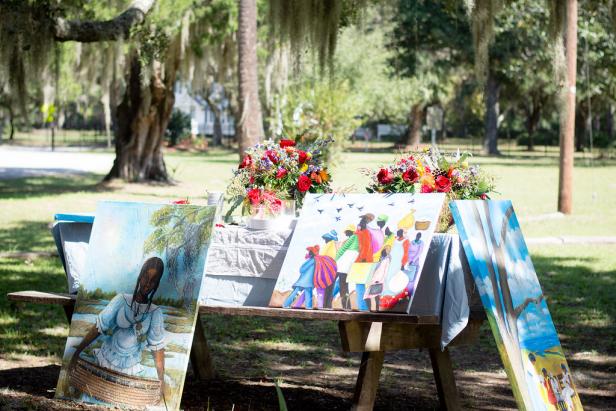 Paintings lean against an outdoor table. 