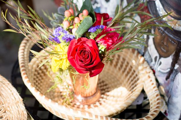 A bouquet of flowers in a container sitting in a sweetgrass basket
