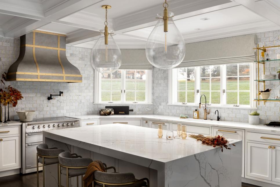 White Kitchen With Large Island Countertop and Bar With Three Stools 