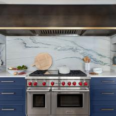 Kitchen With Blue Marble Backsplash and Oversized Range Hood