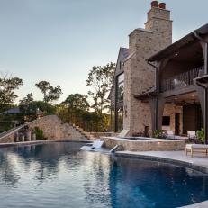Backyard Pool With Slide Concealed in Stone Wall