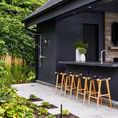 Sleek Black Pool House With Outdoor Shower and Dining Nook