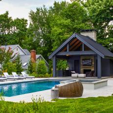 Sleek Black Pool House In Lush Backyard