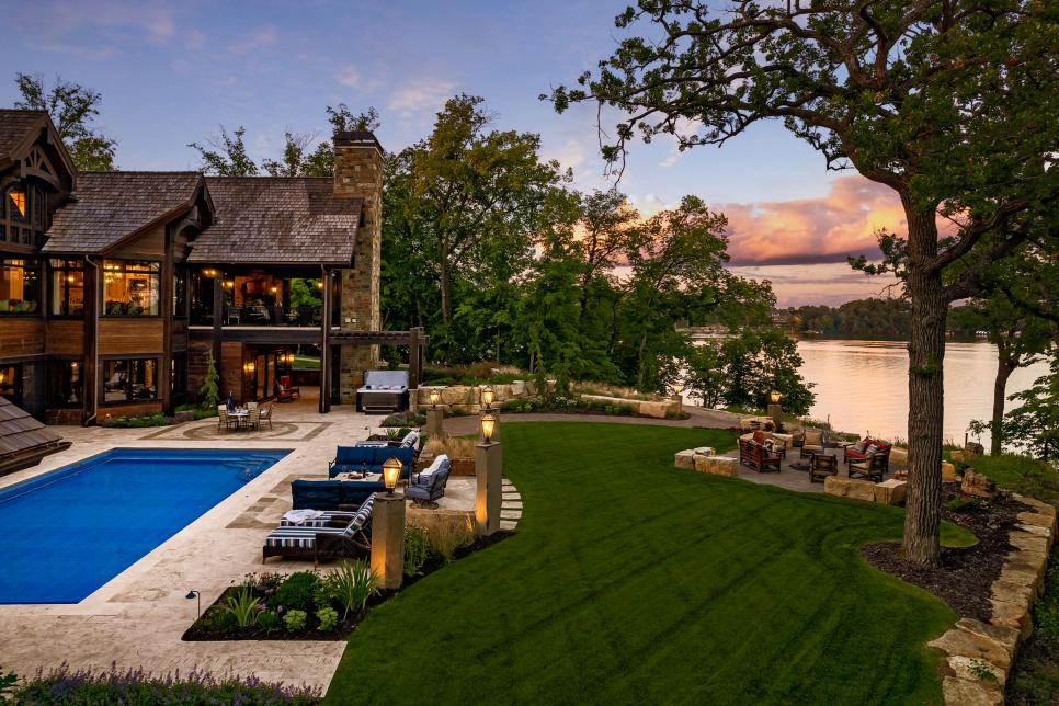 A waterfront cabin's backyard with a pool and lawn.