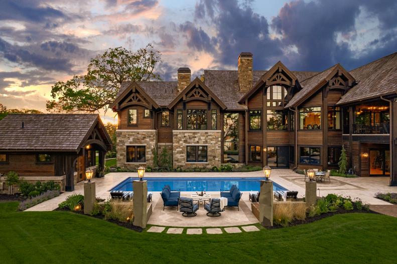 Multi-story cabin with large windows overlooking a pool.