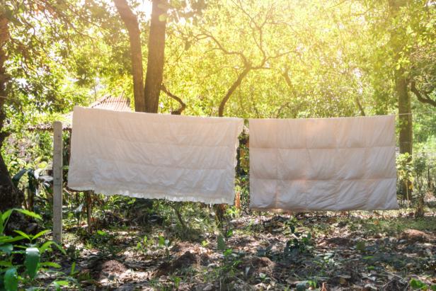 Two white blankets hanging on a clothesline drying In the  afternoon Sun in Countryside, The sun shone on two blankets hanging on the clothesline in countryside at Thailand