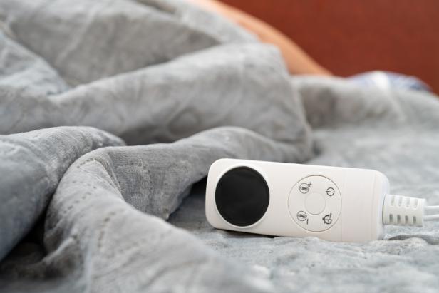 controller of an electric blanket with a human sleeping at the background at horizontal composition