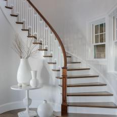 Foyer With a White Curved Staircase and Blue Glass Chandelier 