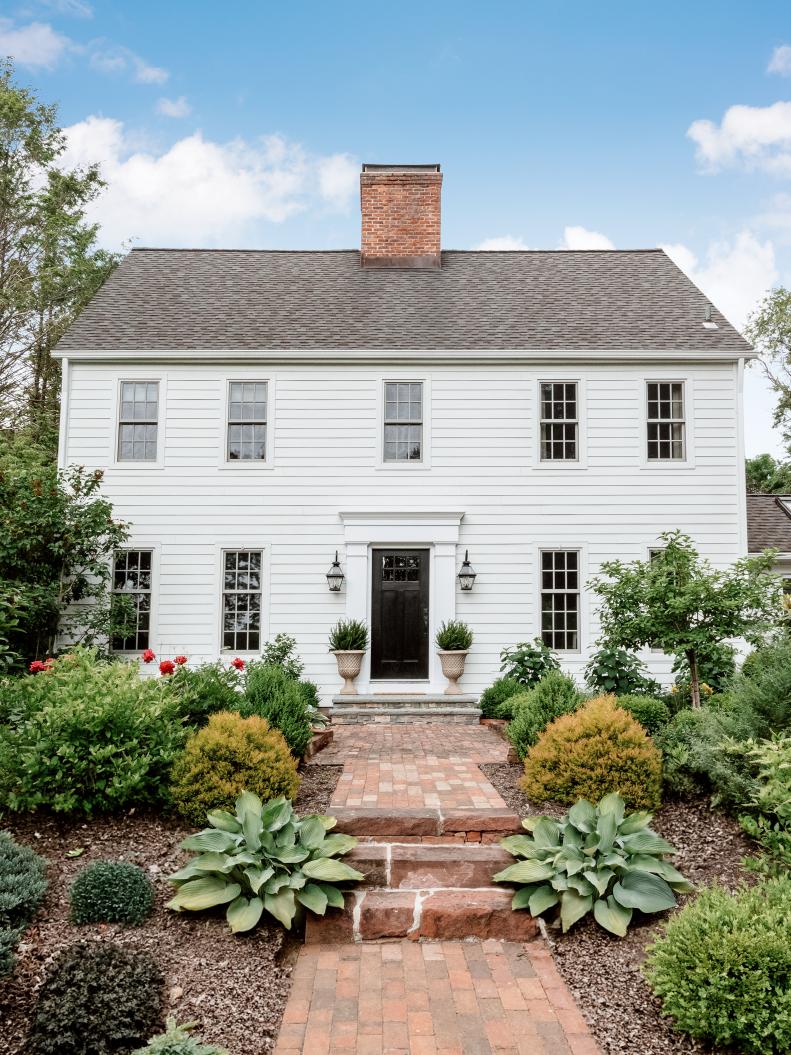White Saltbox Colonial House With a Brick Walkway
