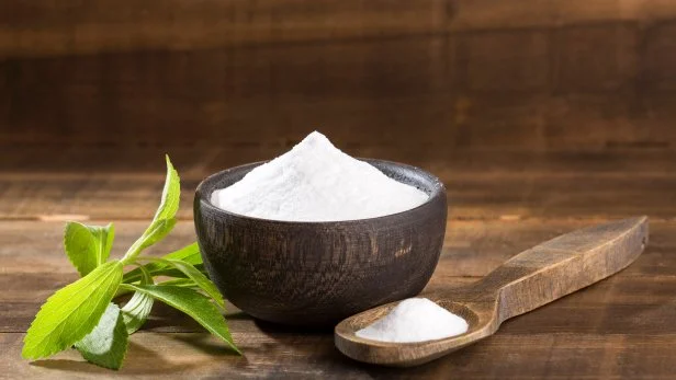 Natural sweetener in powder from stevia plant - Stevia rebaudiana. Wooden background