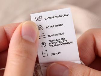 Woman's hands holding clothes label with cleaning instructions.