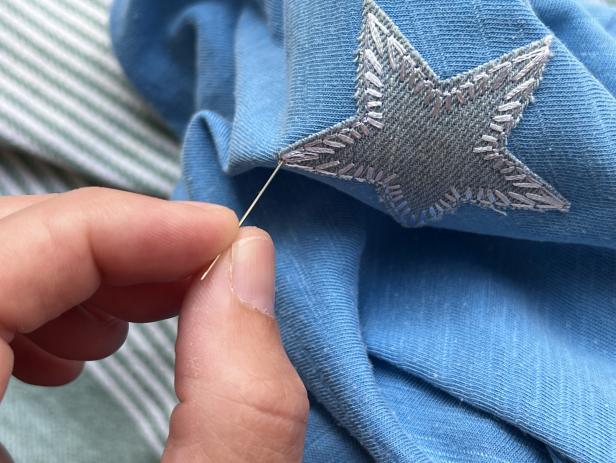 Sewing a patch to cover a hole in a t-shirt.