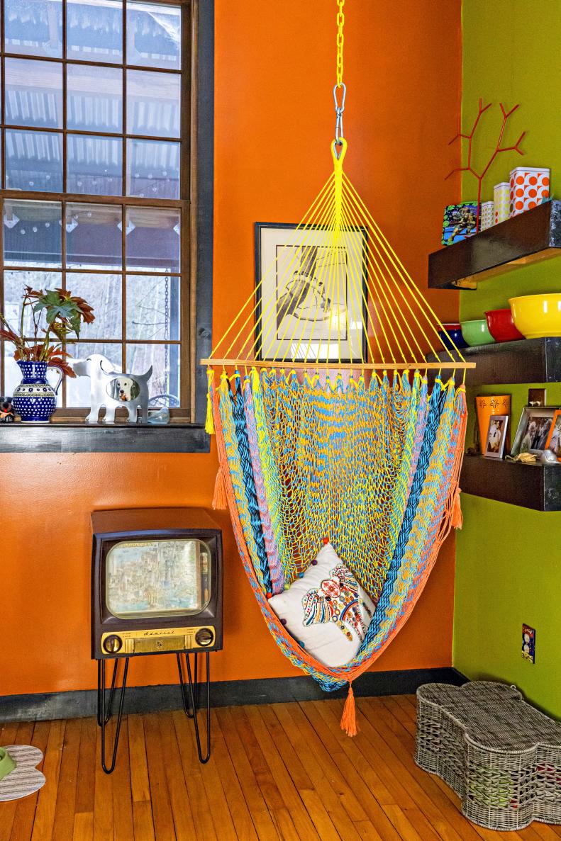 A swinging rope chair hanging from a ceiling near a window.