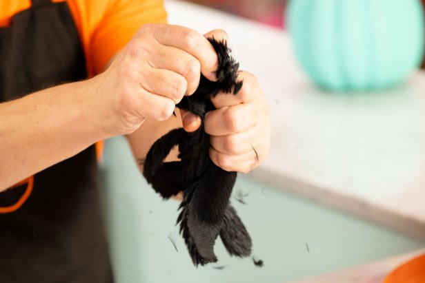 A black fur glove piece is pulled through a man's fist. 