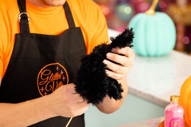 A man uses a skewer to push a black glove right side out. 
