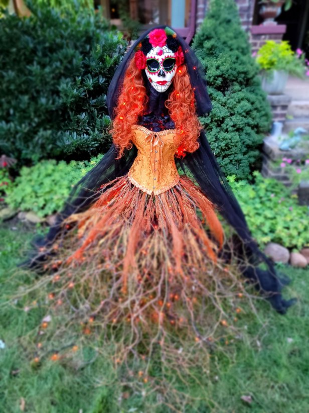 Greet trick-or-treaters with this easy-to-make yard witch with a light-up skirt made of twigs, a fancy corset, and flaming red hair.