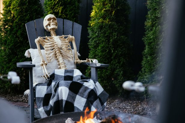 Skeleton roasting marshmallows around a firepit