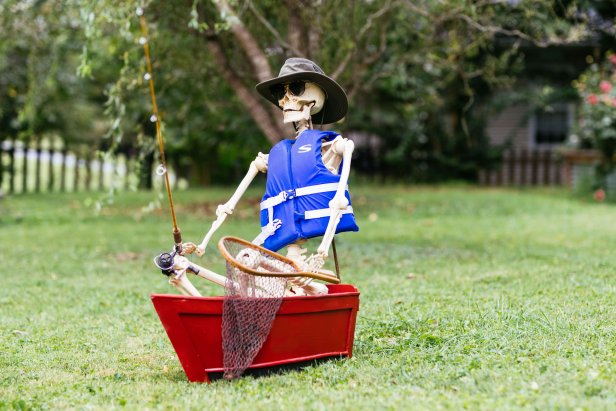 Skeleton wearing a life jacket, sitting in a boat with fishing rod