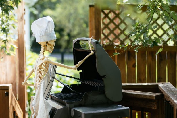 Skeleton wearing apron and grilling