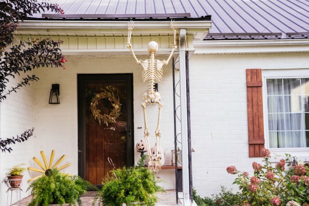 Skeleton hanging from a gutter on the front of a house.