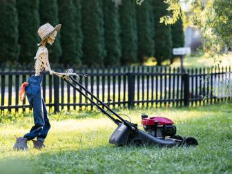 Life-sized skeleton wearing jeans and mowing a yard