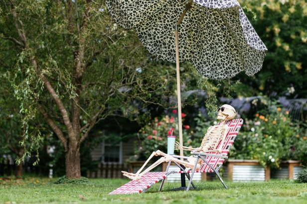 Skeleton sitting in a sun chair with an umbrella and drink