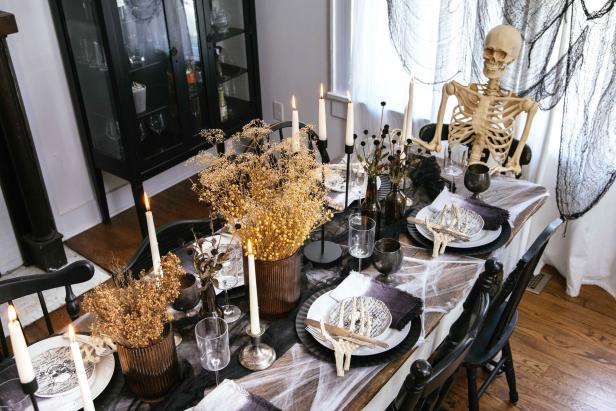 Halloween table with neutral decor and a skeleton at the head.