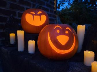 Pumpkins carved with jack-o-'lantern faces light with candles.