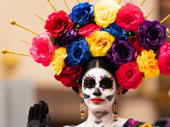 Matamoros, Tamaulipas, Mexico - November 1, 2022: Dia de los Muertos Parade, Catrina wearing traditional clothing and a head dress full of flowers waves at espectators