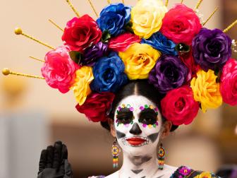 Matamoros, Tamaulipas, Mexico - November 1, 2022: Dia de los Muertos Parade, Catrina wearing traditional clothing and a head dress full of flowers waves at espectators