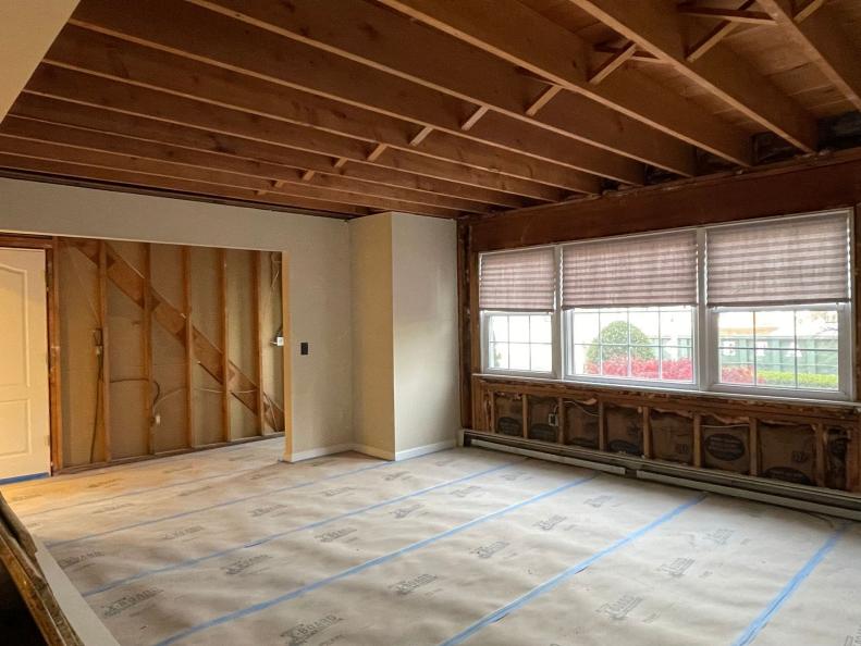 Large room with exposed ceiling beams and drop cloth on floor.