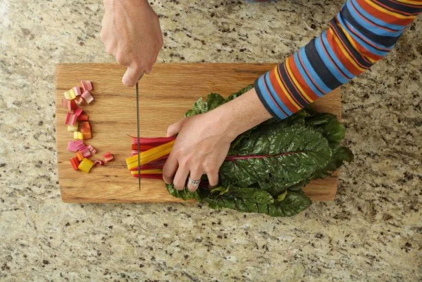 Woman Cutting Rainbow Swiss Chard Stems on a Wooden Cutting Board