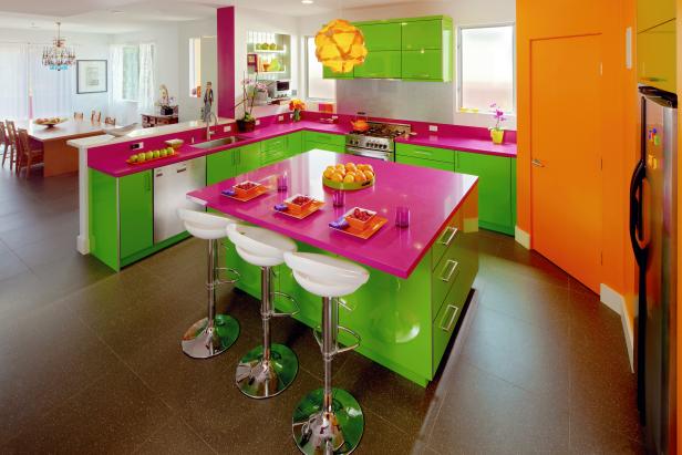 Colorful kitchen with pink countertops and white barstools.