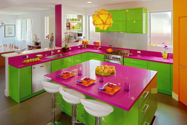 Neon kitchen with pink counters, green storage and orange walls. 