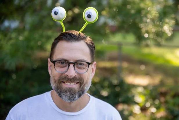 Man wearing a headband with googly monster eye antennas.