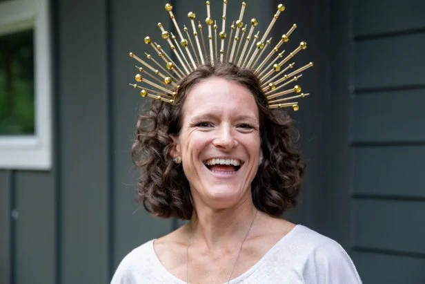 Woman wearing a gold sunburst style crown made from zip ties.