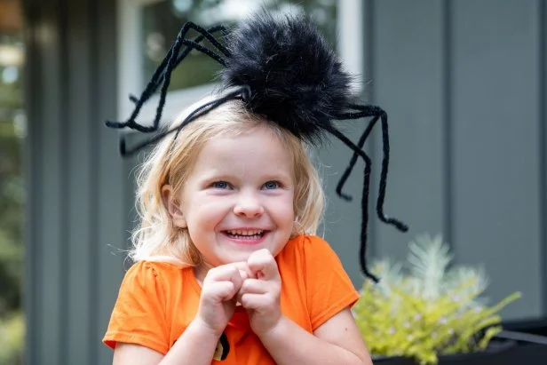 Little girl wearing a giant, fuzzy spider headband.