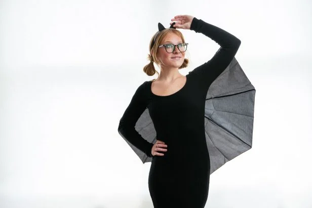 Woman wearing a bat costume made from a black dress