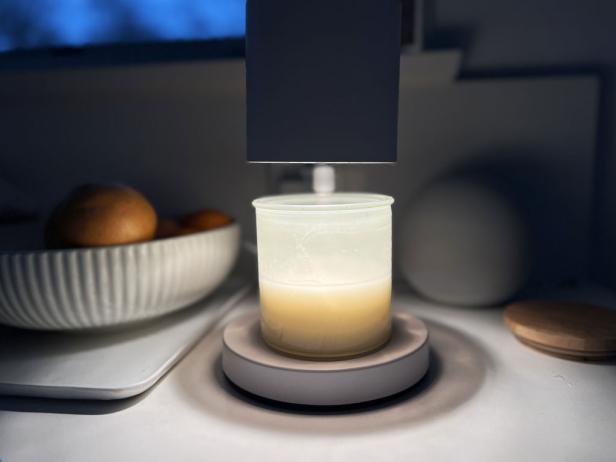 A candle sits under a modern candle warmer lamp.