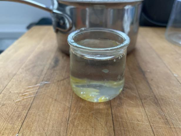 Hot water softens stubborn candle wax in a glass jar.