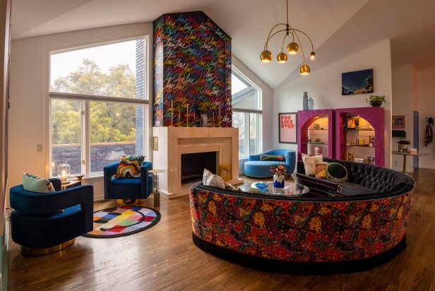 Large room w/ graffiti fireplace, round sofa + chairs, + bright rugs.