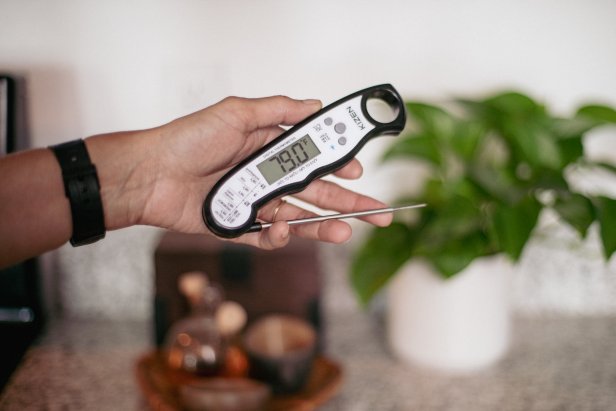 A photo of Chef Cris Ravarré holding a meat thermometer