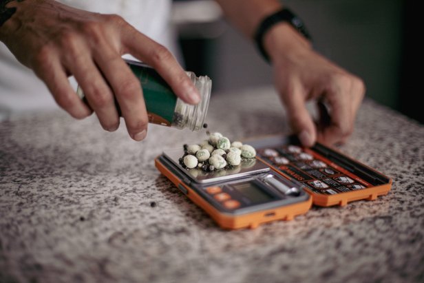 A photo of Chef Cris Ravarré using a gram scale for food.