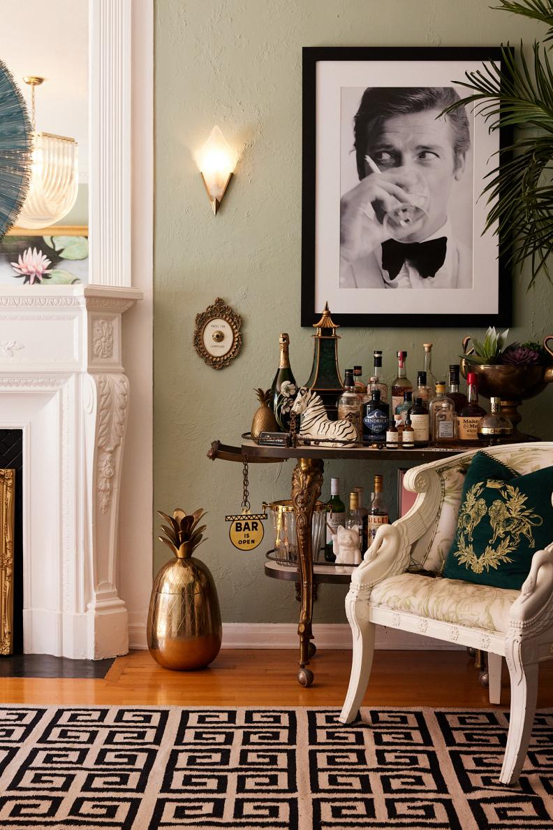 Green room with black and white portrait and Greek key rug.