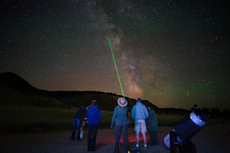 A park ranger using a laser beam identifies a constellation for park visitors attending a stargazing program in Rocky Mountain National Park, Colorado.