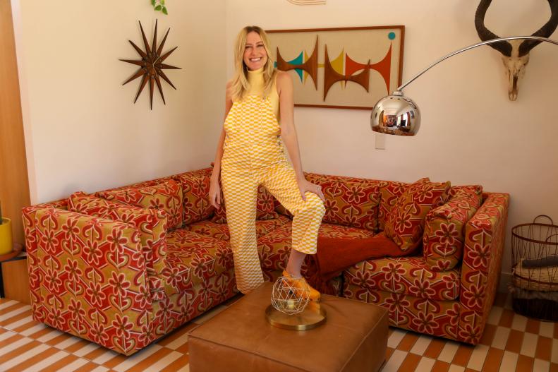 Woman stands with foot on coffee table in orange living room