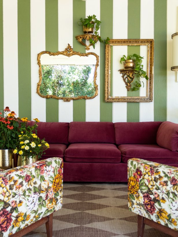 HGTV Magazine shares the details on this eclectic living room with painted green stripes on the walls, vintage gold accents and a pair of floral chairs.