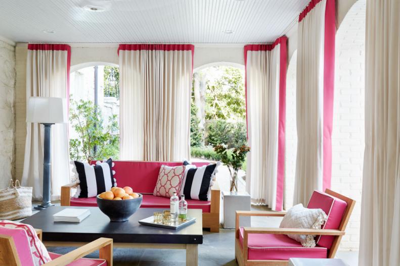 Hot pink upholstery and slate floors bring a modern, feminine touch to this sunroom with high ceilings and almost floor to ceiling windows.